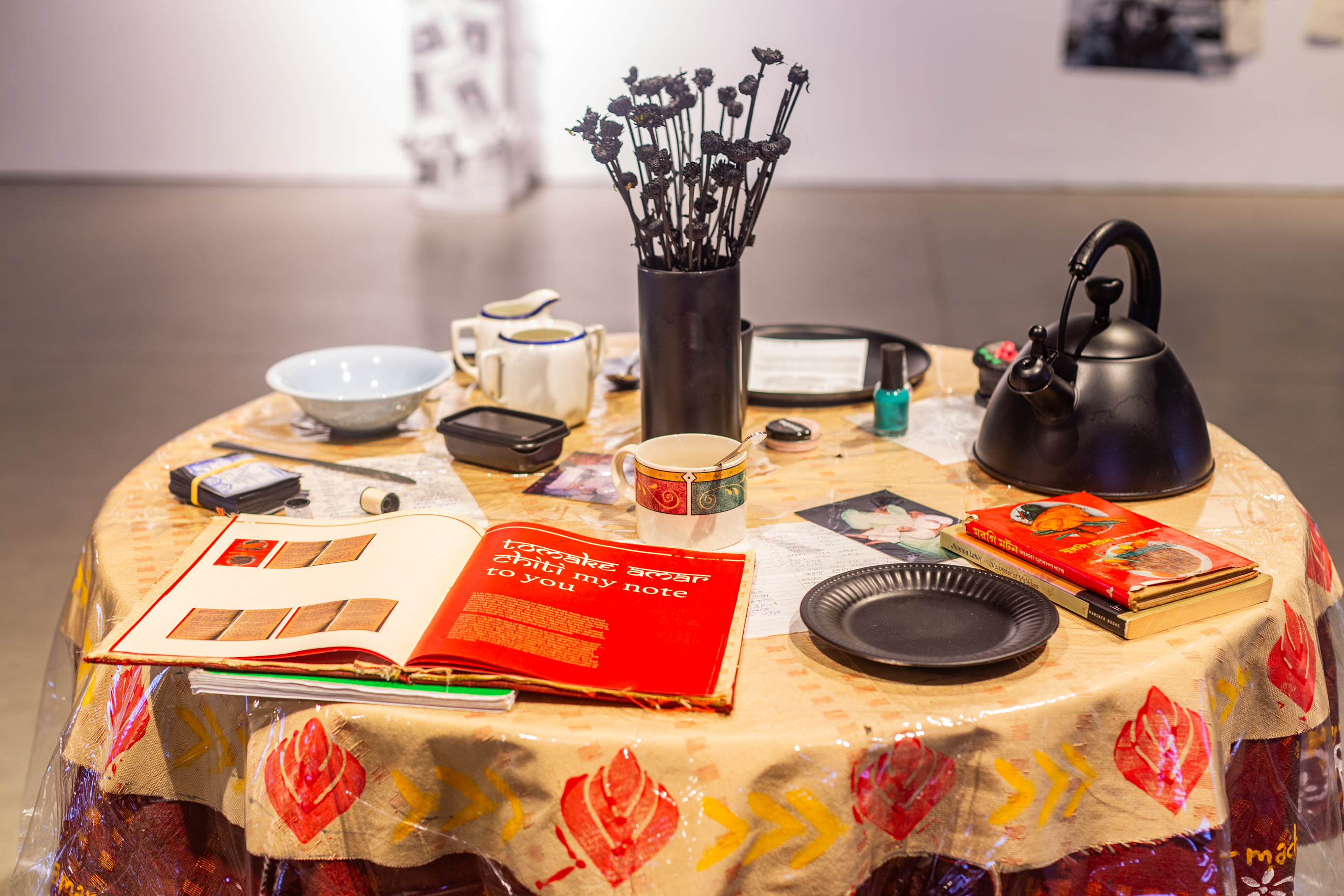 round table with assorted homeware, a vase in the middle with black flowers and a book in the front